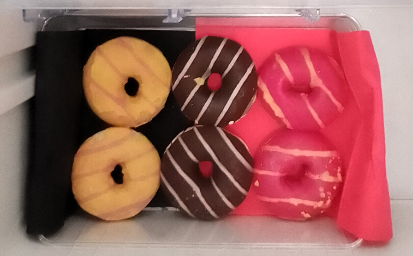 Un cajón con cuatro donuts, dos simples y dos con cobertura de chocolate.
