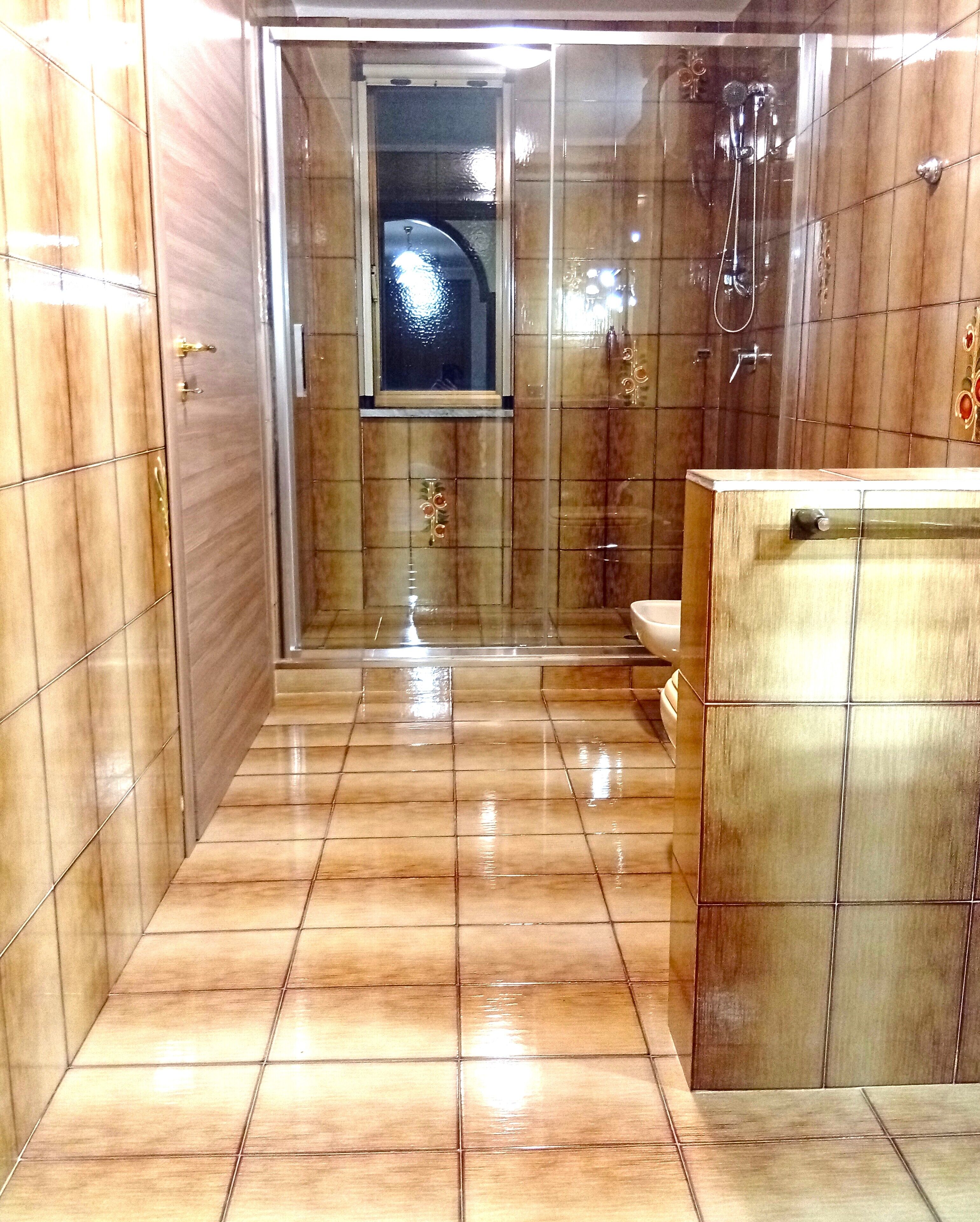 Ein Badezimmer mit Fliesenboden, einer Duschkabine aus Glas und einem Holzbadezimmer-Möbel.