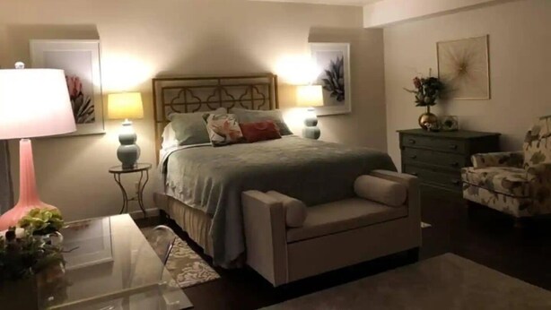 A bedroom with a bed, bedside tables, a chair, and a dresser.