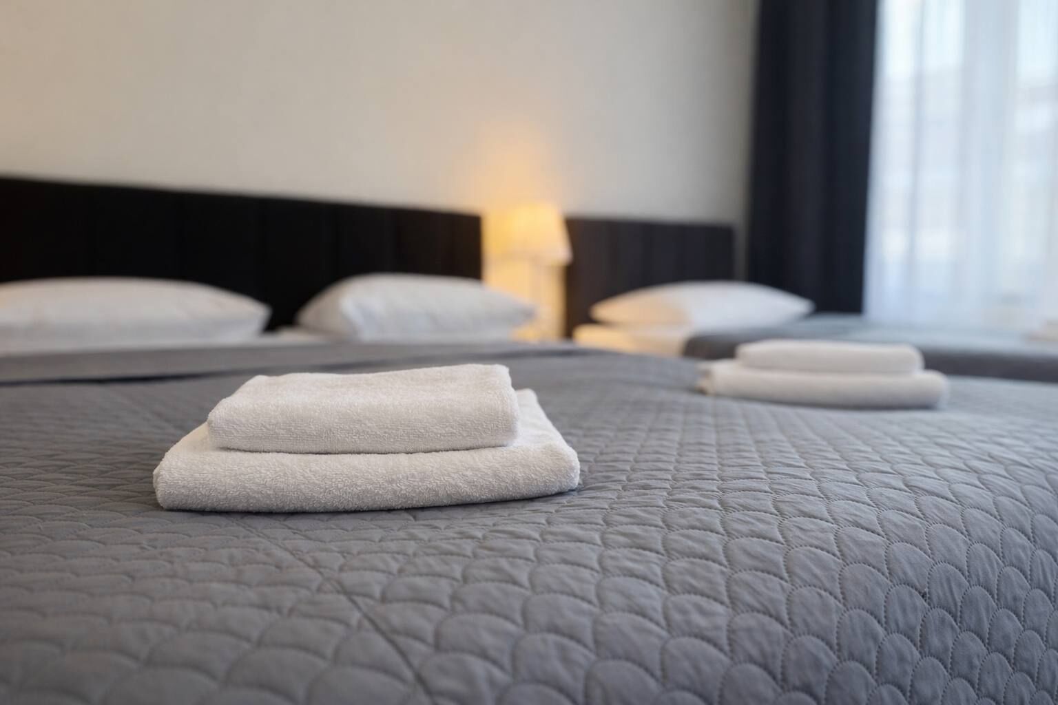 Une chambre d’hôtel avec un lit bien fait, des oreillers et une lampe de chevet.