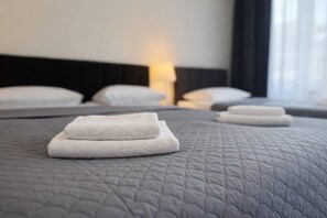 A hotel room with a neatly made bed, pillows, and a bedside lamp. - Hotel Mazowiecki WOW  (Warsaw)