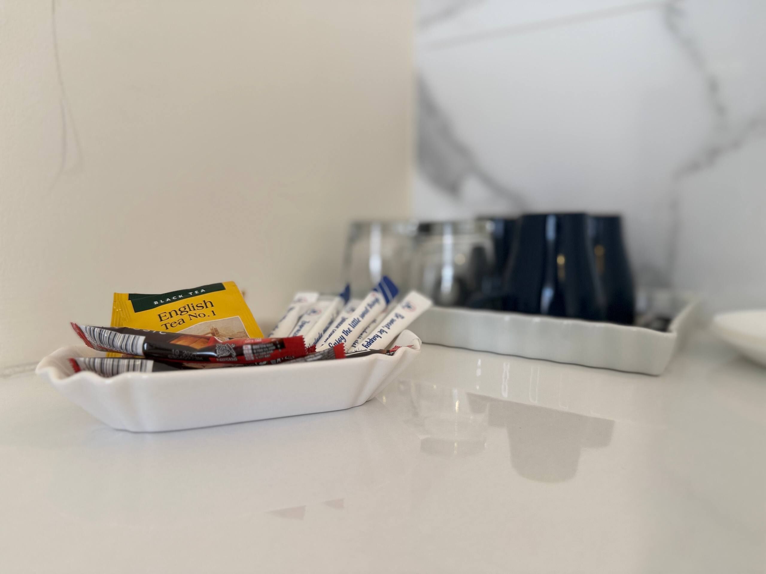 A white tray with tea bags and a card on a reflective surface.