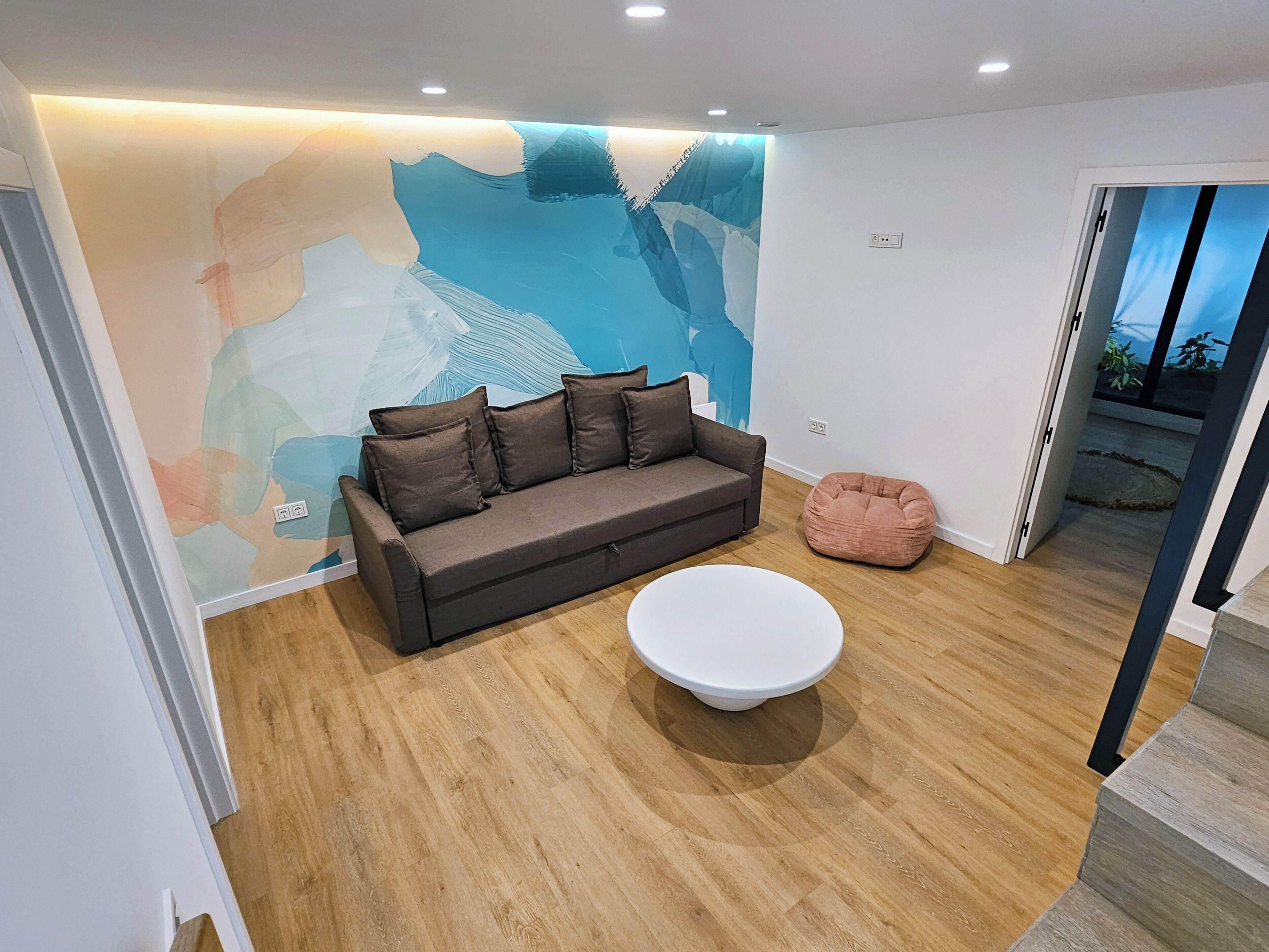 Ein modernes Wohnzimmer mit einem braunen Sofa, einem weißen Couchtisch und einem rosa Sitzsack.