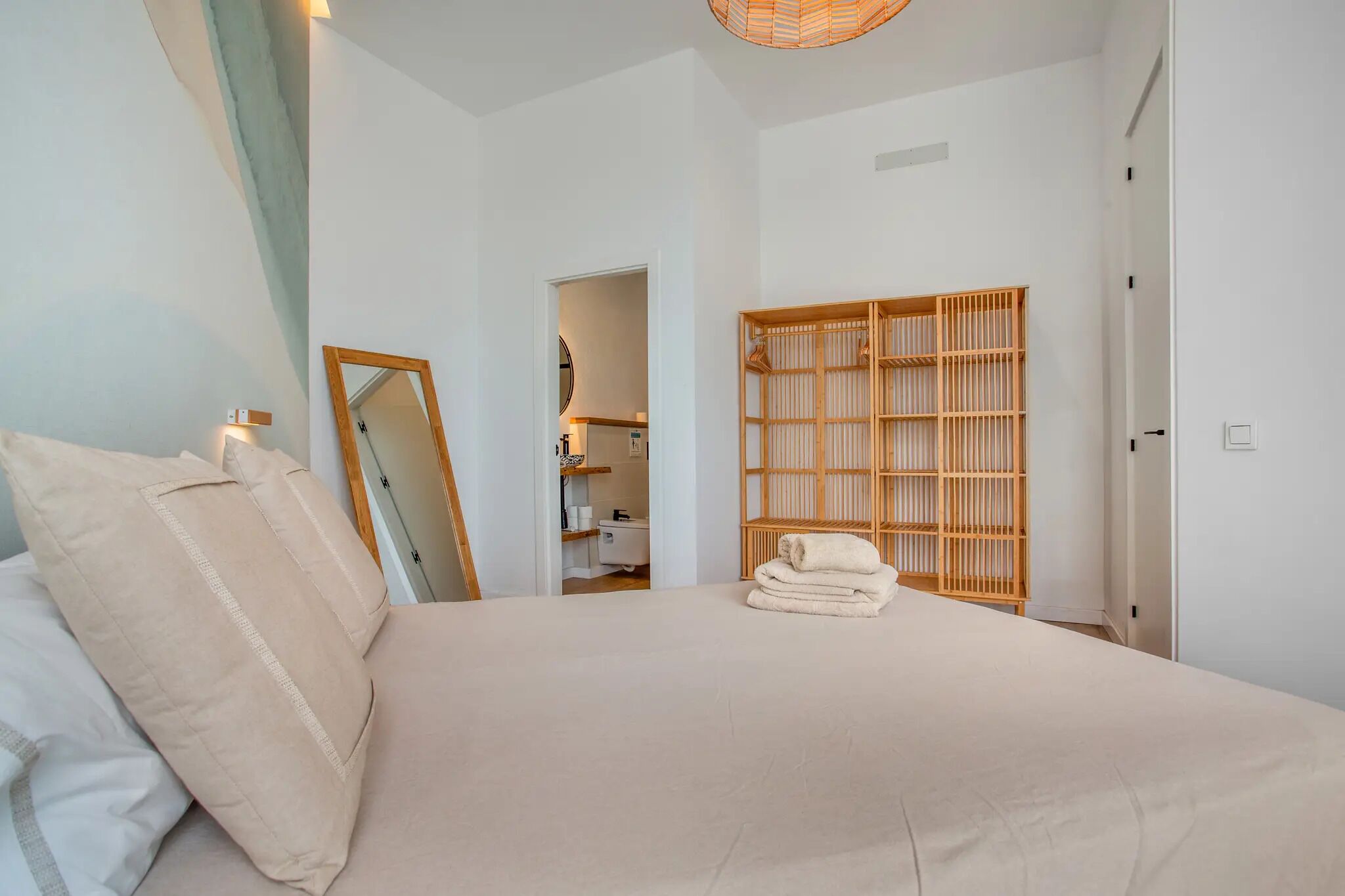 Une chambre à coucher avec un lit, un miroir, une armoire en bois et une serviette sur le lit.