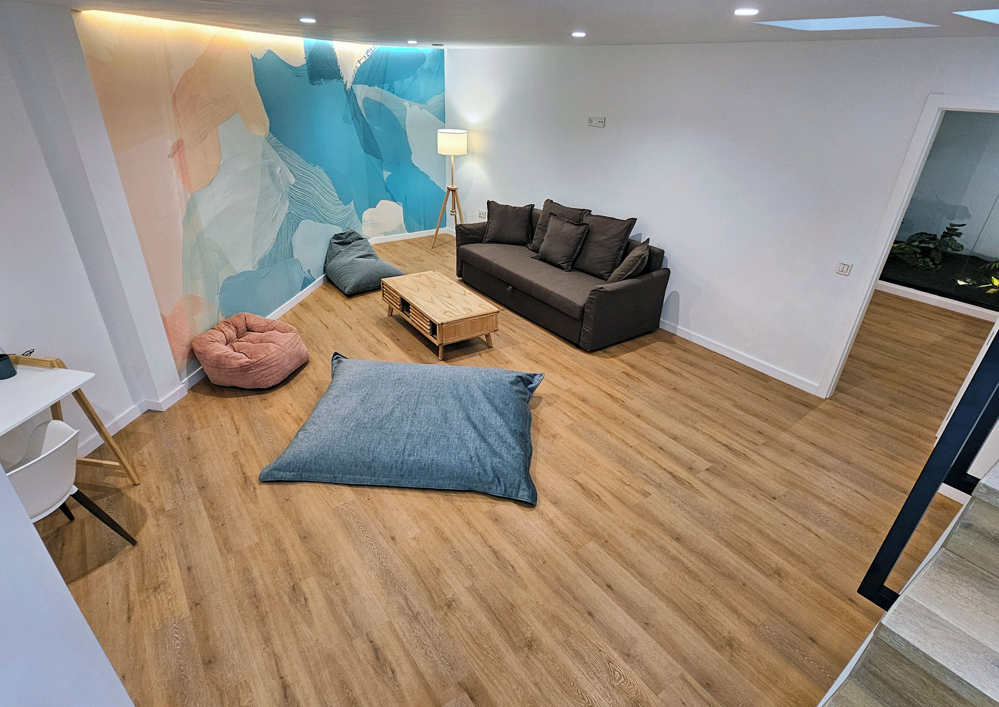 A modern living room with a wooden floor, a sofa, a coffee table, and a bean bag.