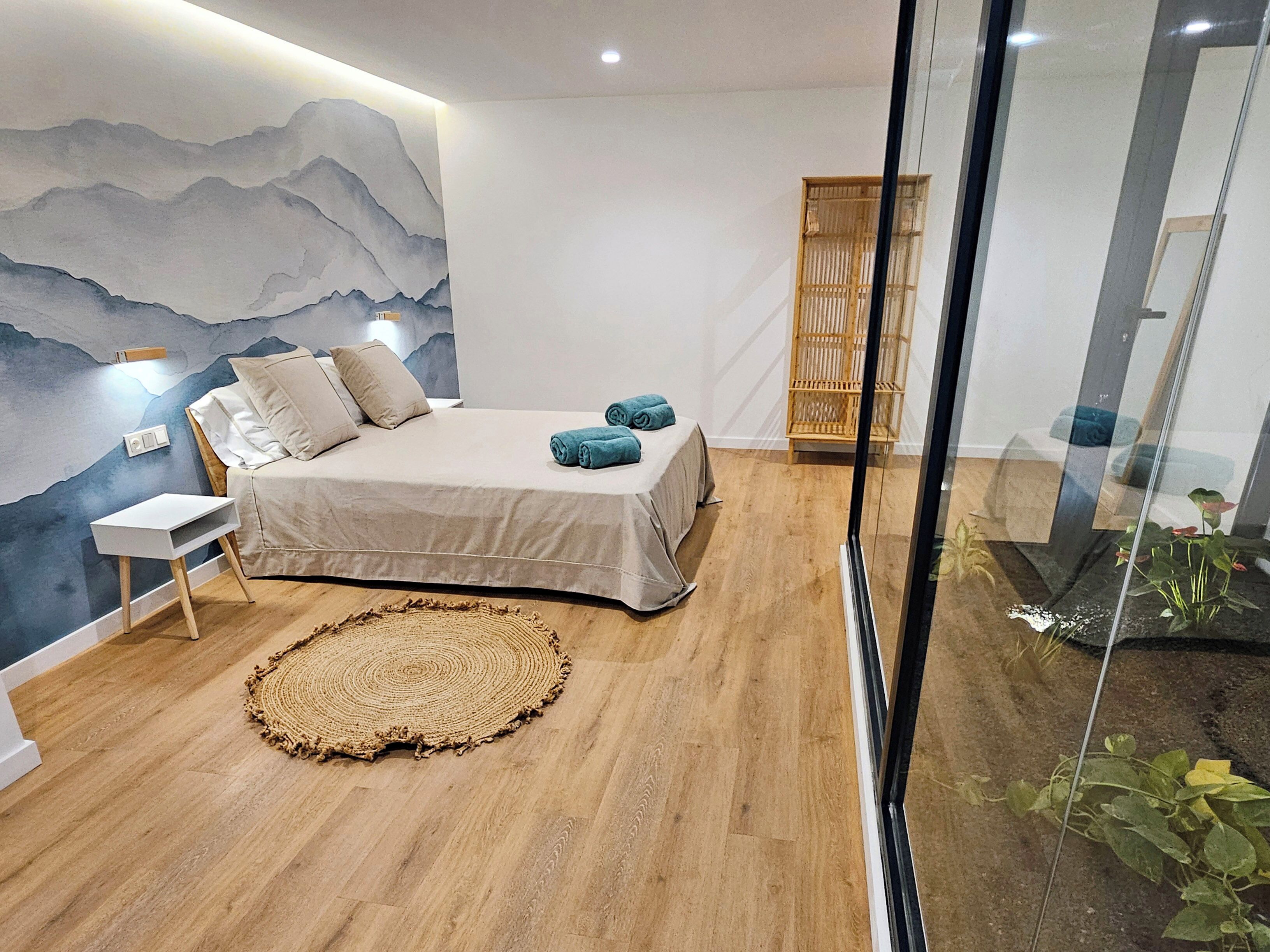 A modern bedroom with a bed, bedside table, and a wall mural.