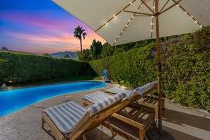 A poolside area with lounge chairs and a canopy.