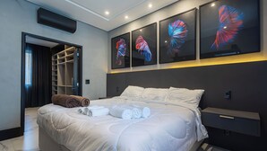 Een moderne hotelkamer met een groot bed, een inloopkast en drie aan de muur bevestigde kunstwerken.