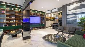 Een moderne woonkamer met een grote boekenkast, een flatscreen televisie, een eethoek en een groene bank.