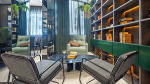 Een moderne bibliotheek met een marmeren tafel, lederen stoelen en een groene boekenkast vol boeken.