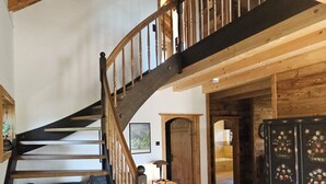 Eine Holztreppe mit schwarzer Handlauf, die zu einer oberen Ebene führt.