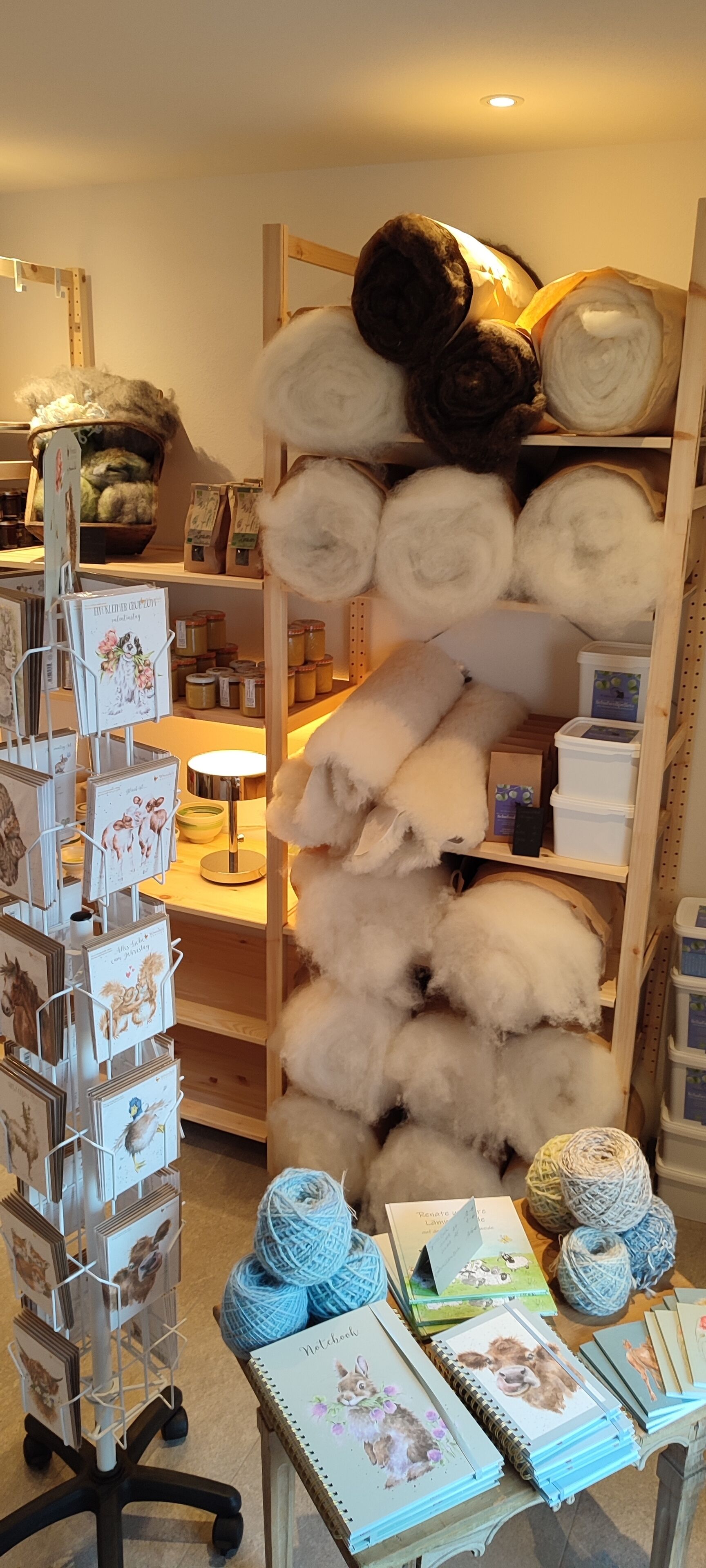 A craft store with shelves of yarn, knitting supplies, and a display of cards.