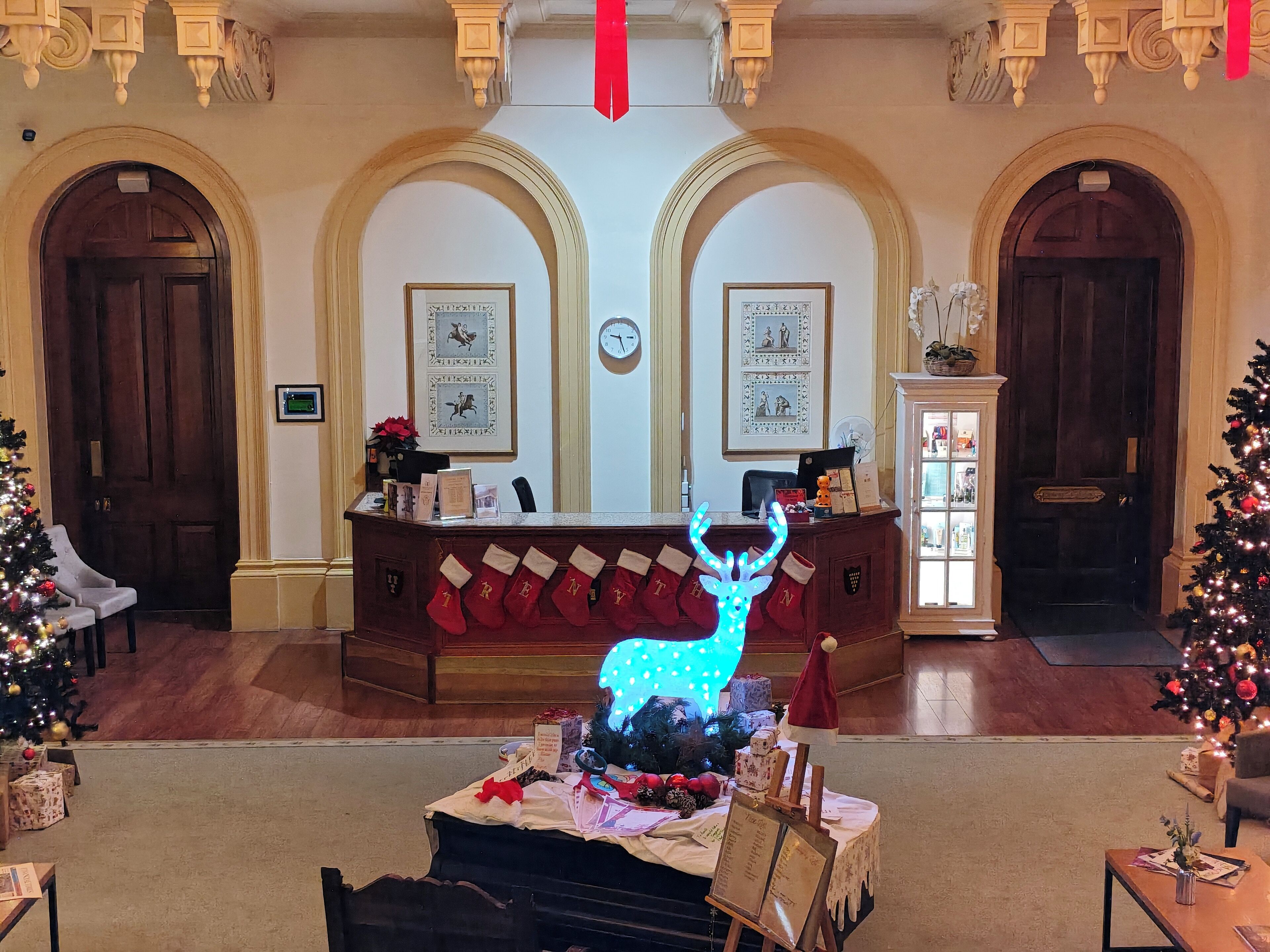 A lobby with a reception desk, Christmas decorations, and a clock on the wall.