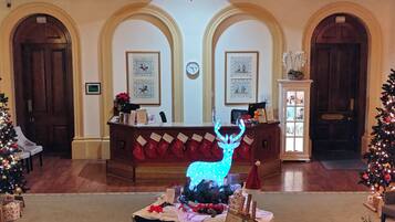 Un hall con mostrador de recepción, adornos navideños y un reloj en la pared.