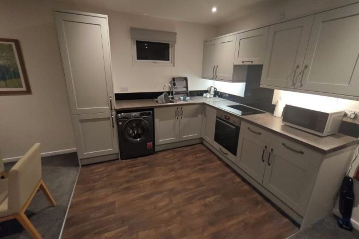 A compact kitchen with a washing machine, microwave, and a sink.
