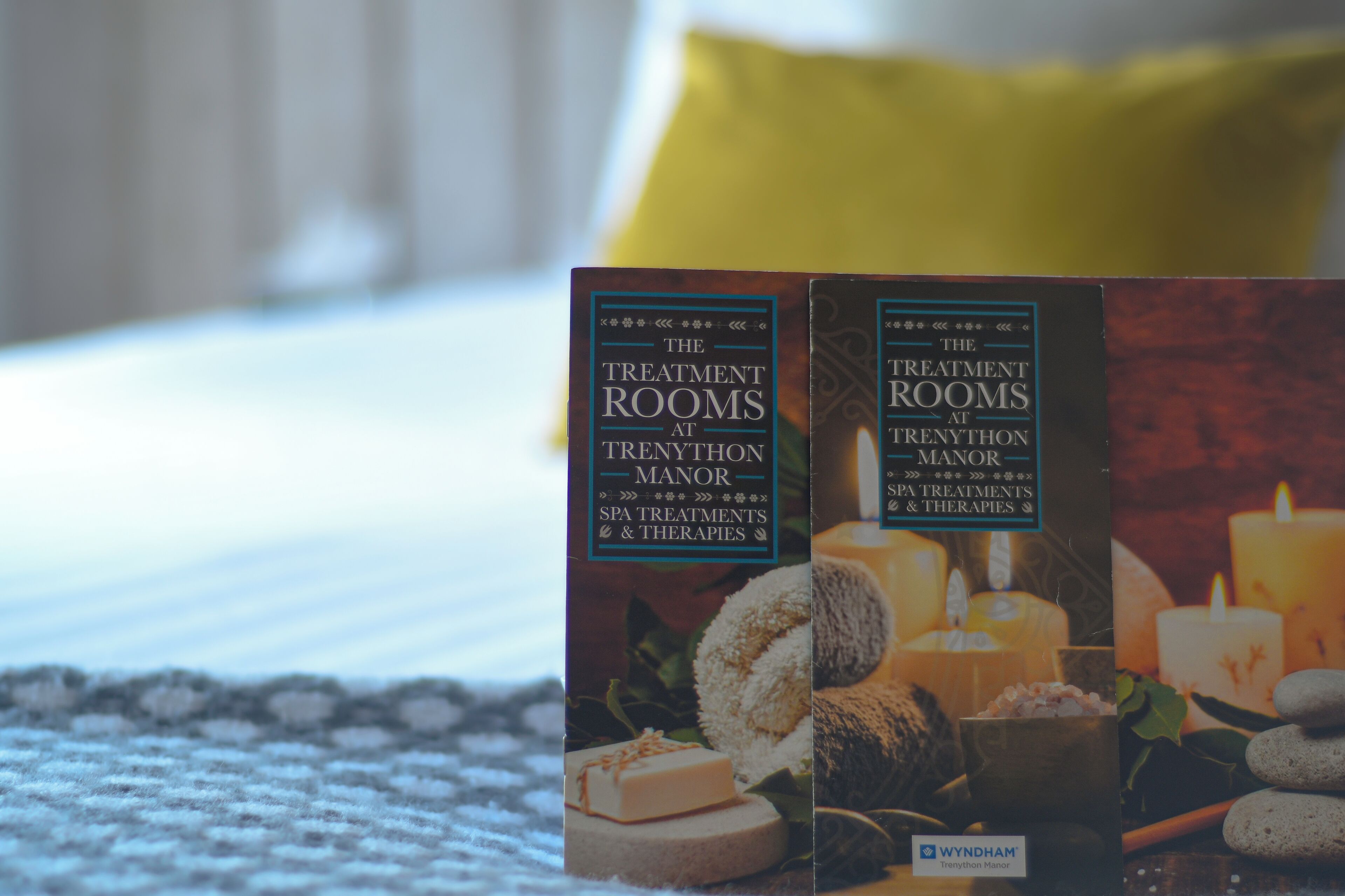 Two brochures titled "The Treatment Rooms at Trenython Manor Spa Treatments & Therapies" on a textured fabric surface.