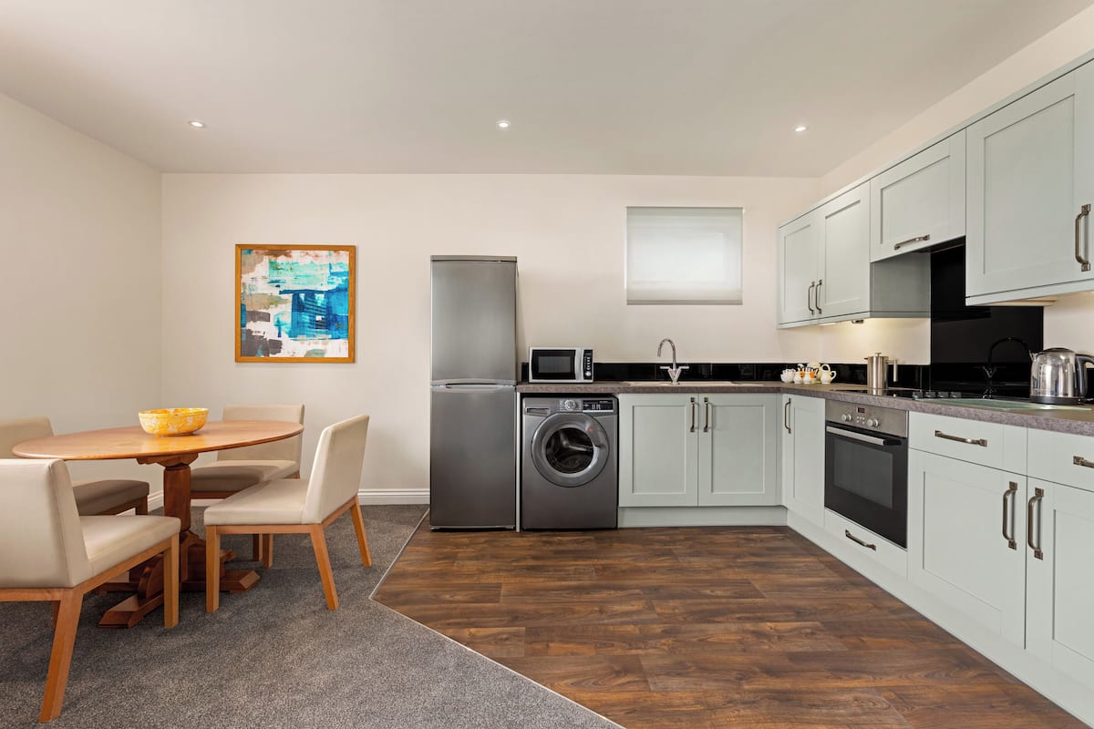A compact kitchen with a dining area, a washing machine, and a refrigerator.