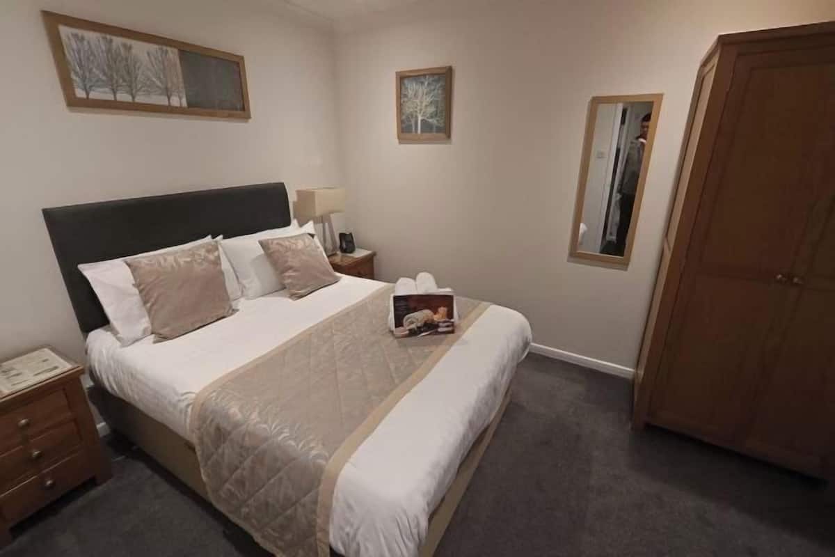 A neatly arranged bedroom with a bed, bedside tables, a wardrobe, and framed artwork on the walls.