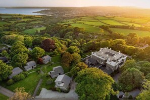 An aerial view of a rural estate with multiple houses, a large manor, and surrounding fields.