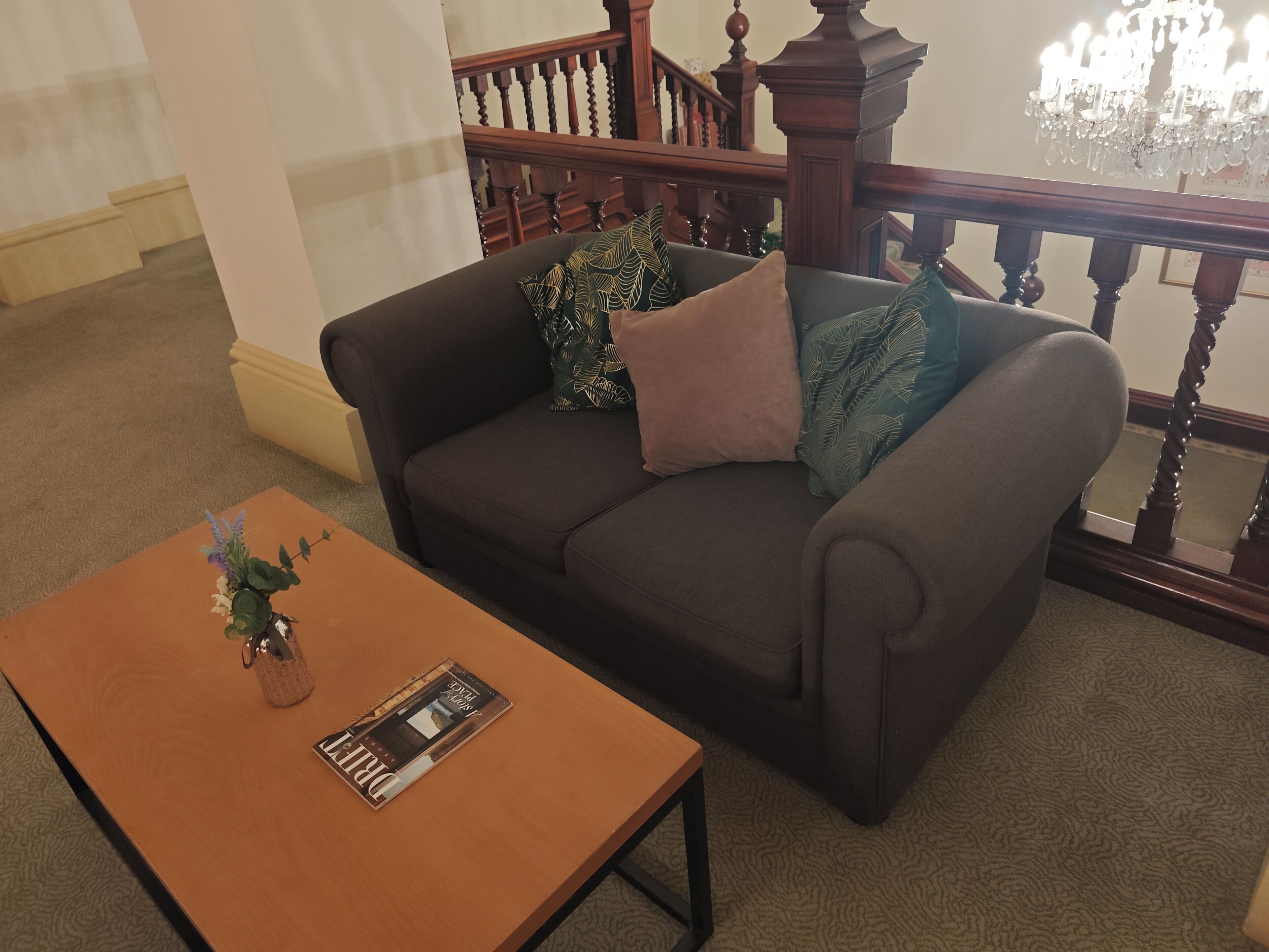A living room with a dark brown sofa, a wooden coffee table, and a staircase with wooden railings.