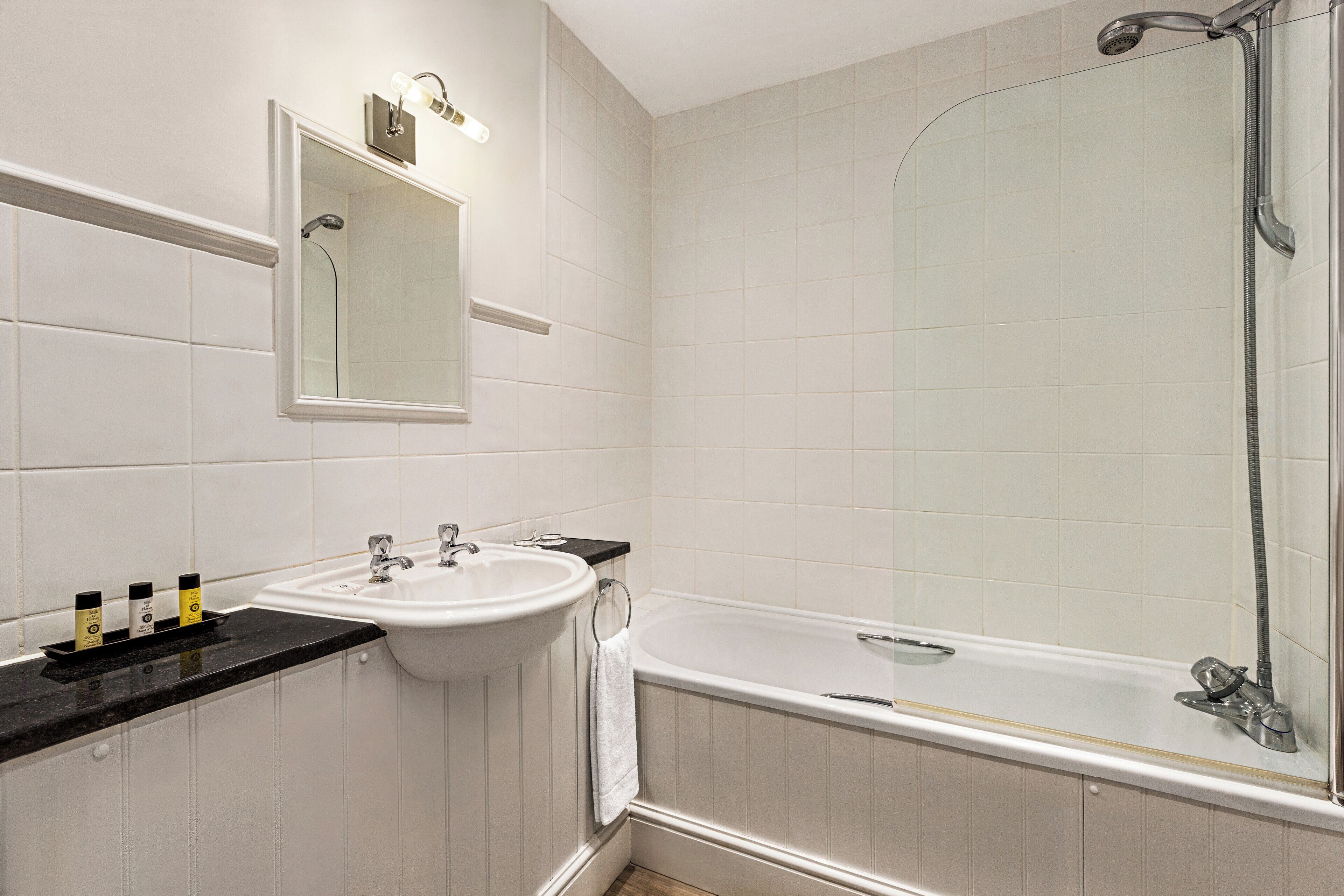 A bathroom with a white sink, mirror, and bathtub.