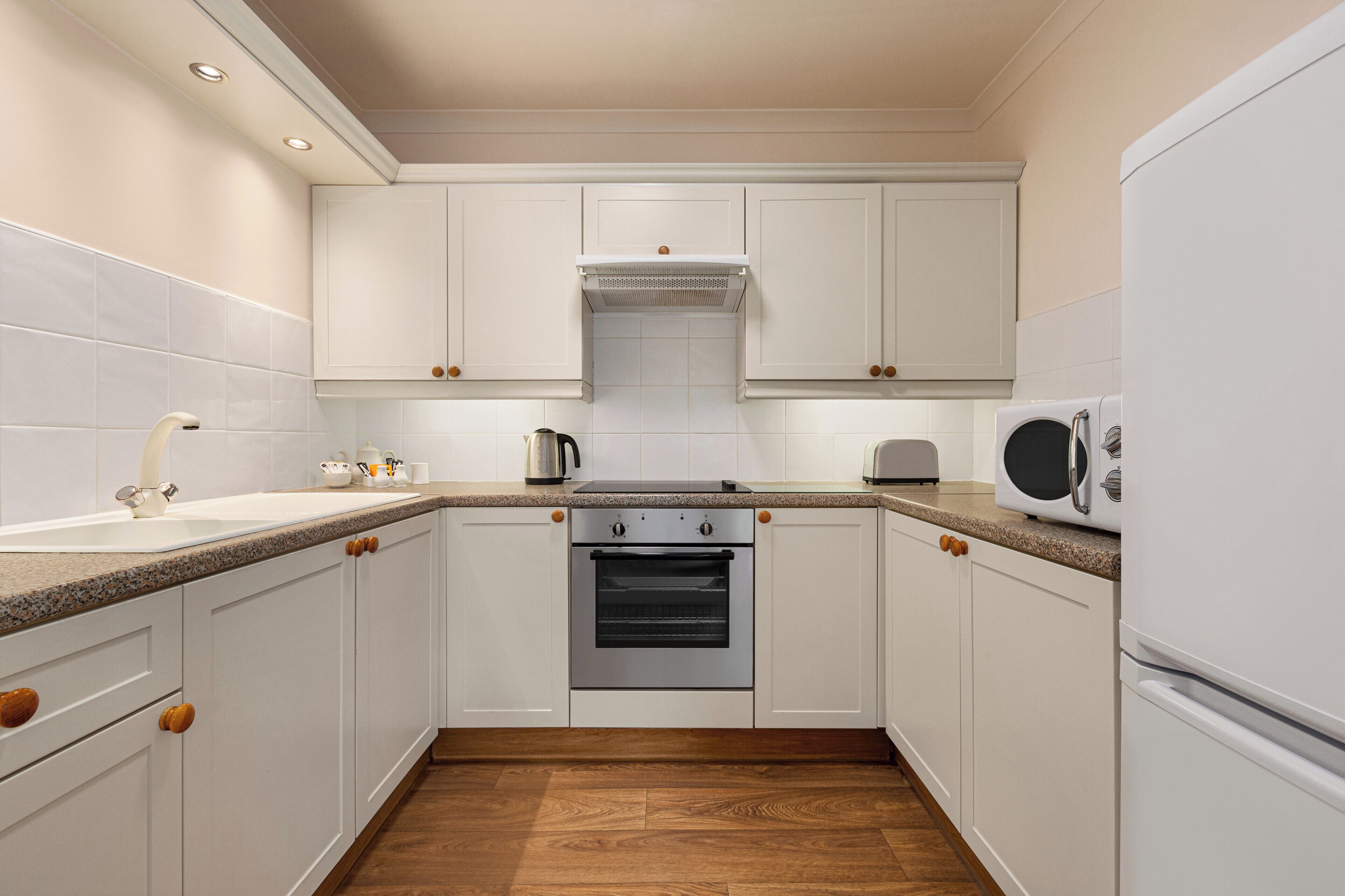 A kitchen with white cabinets, a built-in oven, a microwave, and a sink.