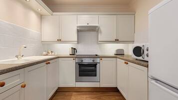 A kitchen with white cabinets, a built-in oven, a microwave, and a sink.