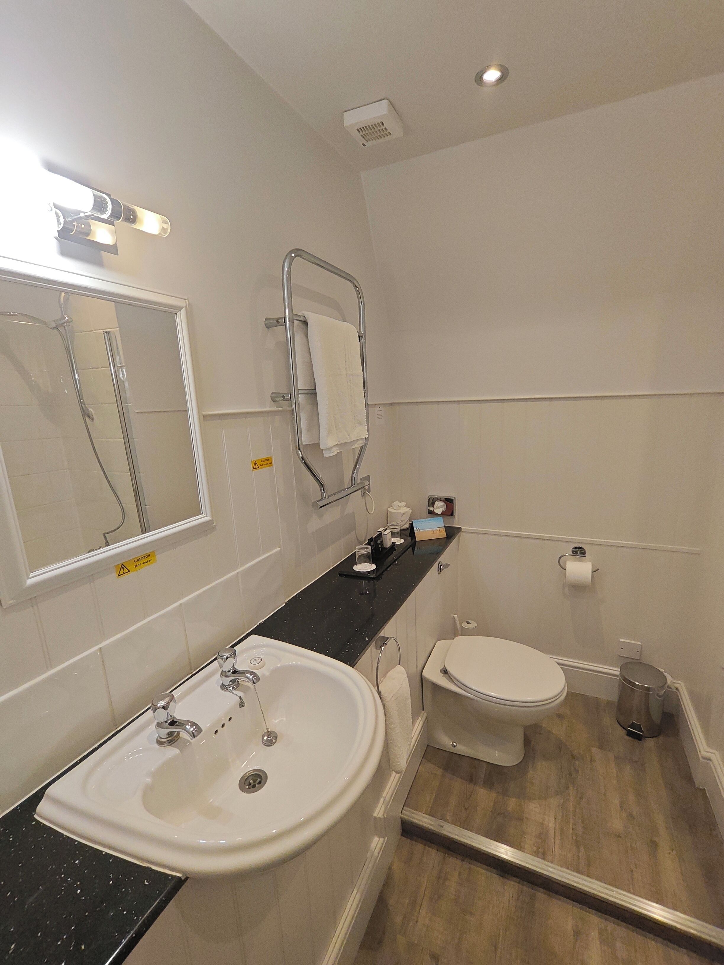 A modern bathroom with a large sink, a toilet, and a shower.