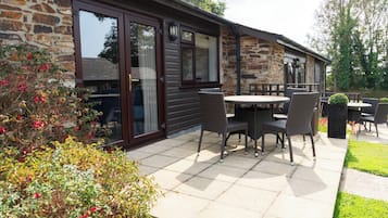 A stone building with a patio area featuring outdoor seating.