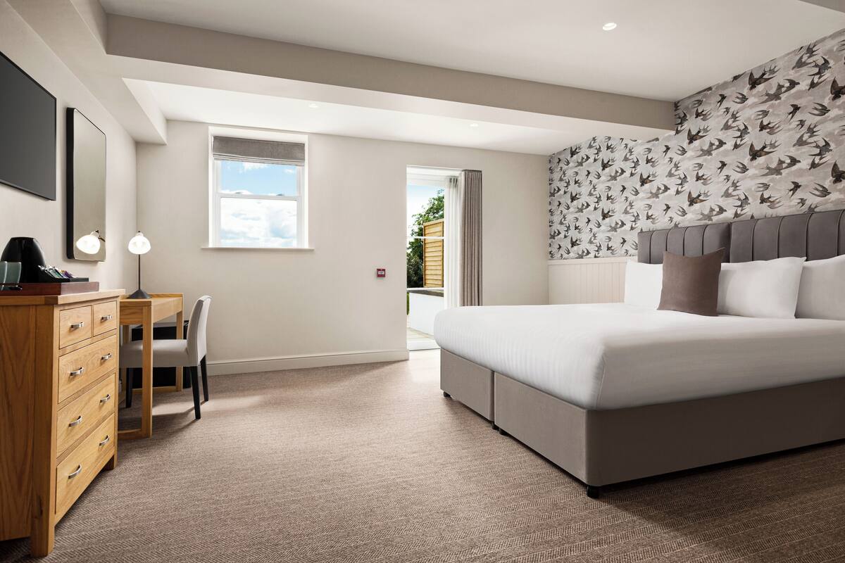 A bedroom with a large bed, a desk, and a chair.