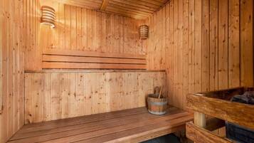 A wooden sauna with benches and a bucket of wood shavings.