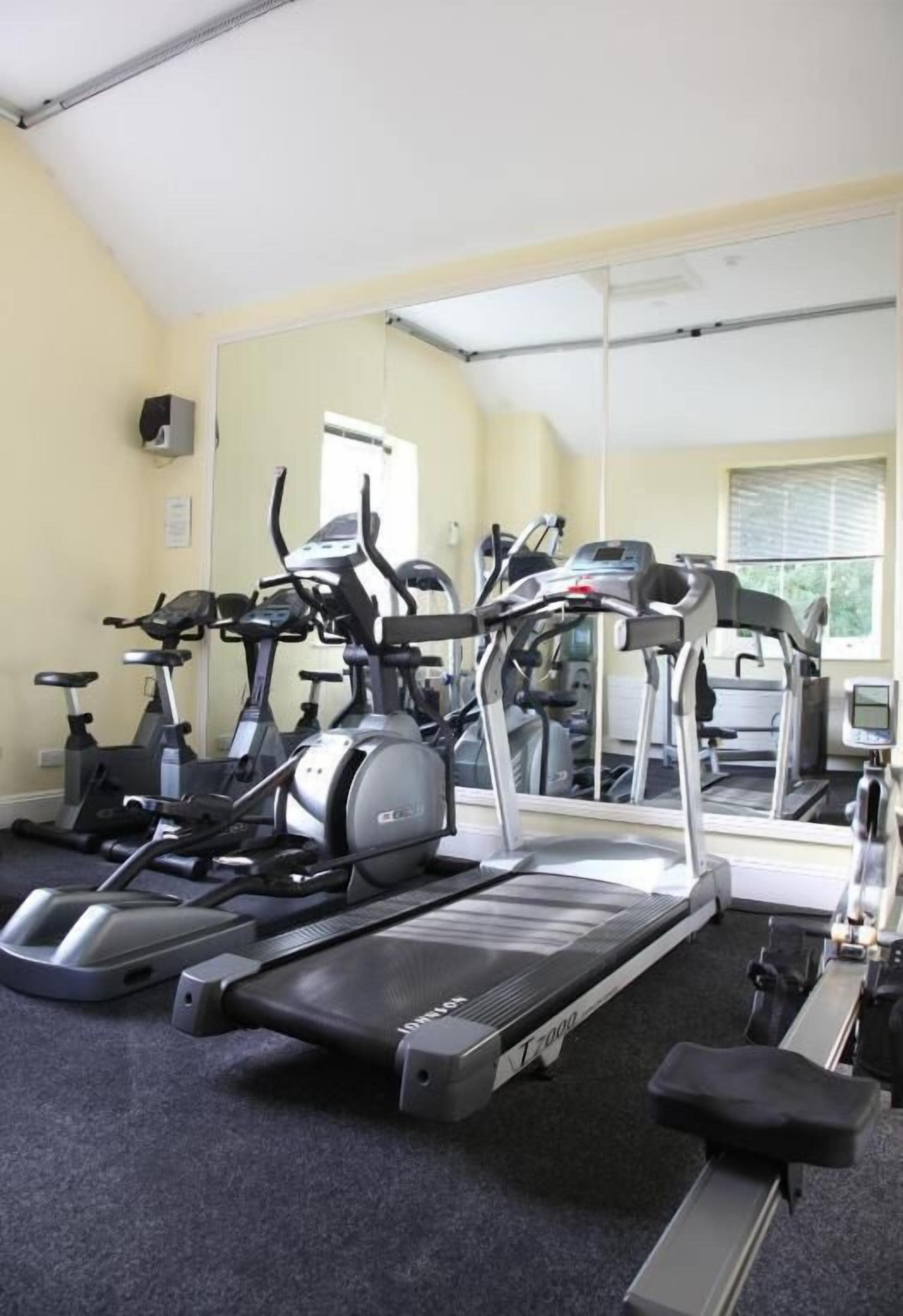 Une salle de sport équipée de tapis de course, de vélos d’appartement et d’appareils elliptiques.