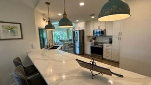 Una cocina moderna con armarios blancos, electrodomésticos de acero inoxidable y una isla de mármol.