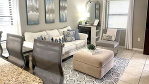 A living room with a sofa, chairs, a coffee table, and artwork on the walls.