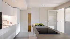 Une cuisine moderne dotée d’un îlot central, d’appareils électroménagers intégrés et d’un design minimaliste.