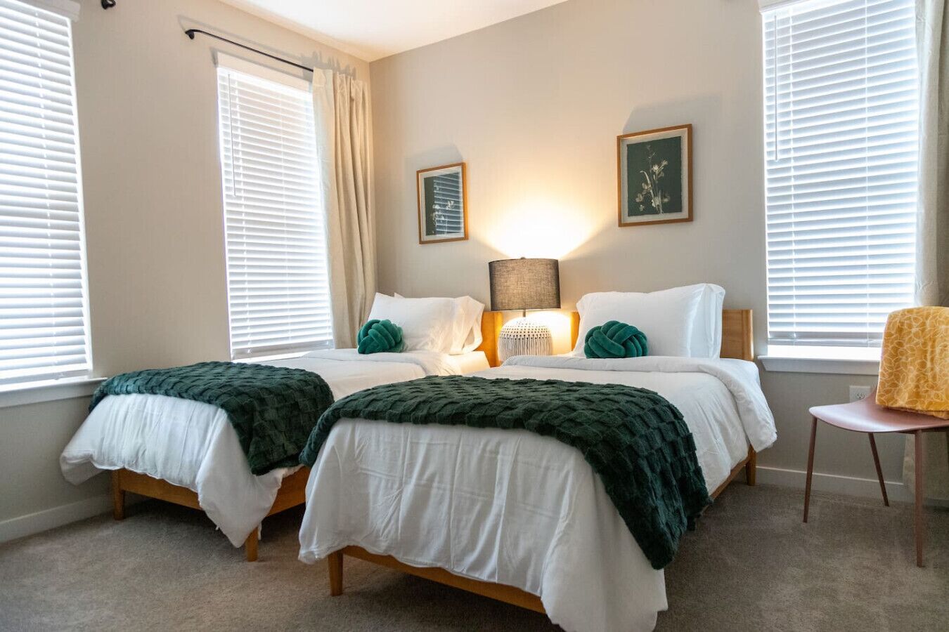 Une chambre avec deux lits, une lampe de chevet, une chaise et un tableau encadré au mur.