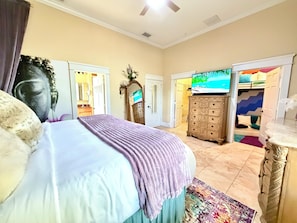 A bedroom with a bed, a dresser, a television, and a Buddha statue. - Luxury Hyde Park Dual Townhouse Retreat w Gym & Sauna Sleeps 16 Walkable (Tampa)