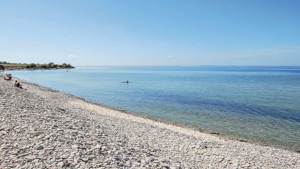 A pebbled beach with clear water and a distant shoreline. - Stunning home in Löttorp with WiFi (Löttorp)