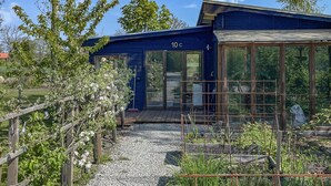 A blue building with a number '10c' on the door, a wooden fence, and a garden area with plants and a gravel path. - Stunning home in Löttorp with WiFi (Löttorp)