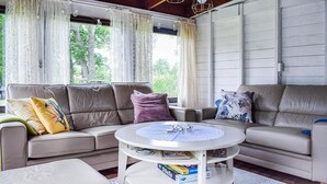 A cozy living room with a beige sofa, a round coffee table, and a view of greenery outside. - Stunning home in Löttorp with WiFi (Löttorp)