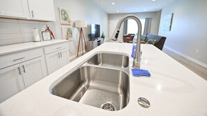 Una cocina moderna con un lavamanos doble, muebles blancos y encimera.