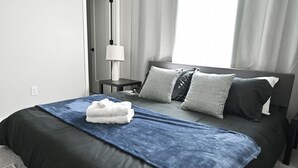 Una cama bien hecha con una colcha azul, dos almohadas y una toalla doblada.