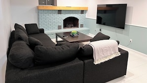 A modern living room with a sectional sofa, a fireplace, and a flat-screen TV.