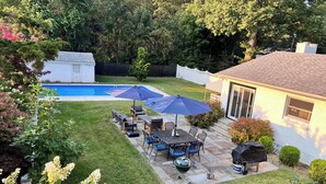 A backyard with a swimming pool, patio furniture, and a barbecue grill.