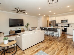 A modern living room with a sofa, a TV, a ceiling fan, and a dining area with a table and chairs. - “Opulence in Oxford” (Oxford)