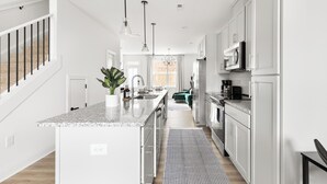 Een moderne keuken met witte kasten, een granieten aanrechtblad en roestvrijstalen apparatuur.