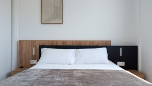 Une chambre moderne avec une tête de lit en bois, du linge de lit blanc et un tapis à motifs.