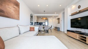Un salon moderne avec un canapé, un coin repas et une cuisine en arrière-plan.