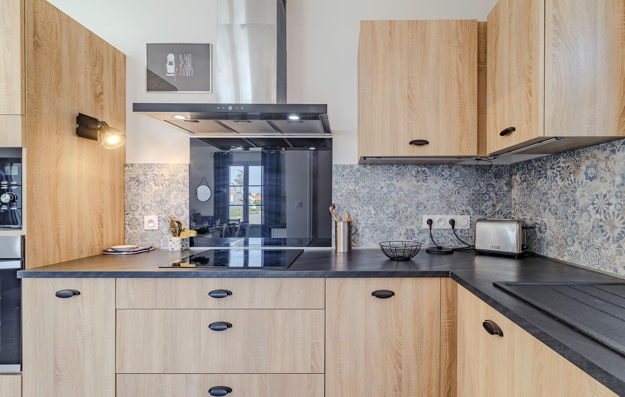 Una cocina moderna con armarios de madera, una campana extractora de acero inoxidable y un salpicadero decorado.