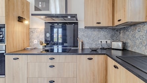 Una cocina moderna con armarios de madera, una campana extractora de acero inoxidable y un salpicadero decorado.